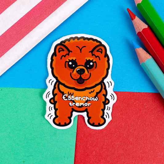 Essential Tremors sticker shown on a red and blue background. The sticker is in the shape of a Chow Chow dog. The dog is orange and fluffy with big eyes and a cute smile. There are black squiggly lines around the dog to portray tremors. 'Essenchow tremor' is written across the chest in white writing.