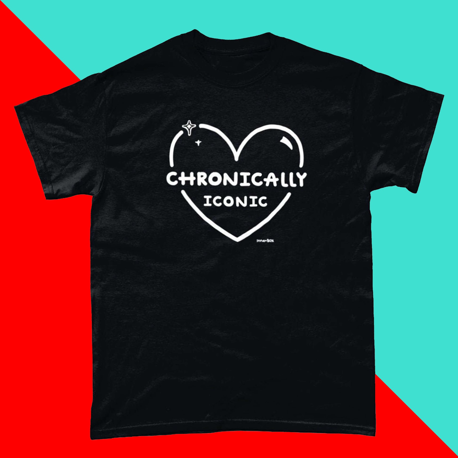 The Chronically Iconic black tee on a red and blue background. The short sleeve t-shirt features a white heart outline with sparkles and centre text reading 'chronically iconic' with the innabox logo underneath. The design is raising awareness for chronic illness and invisible illness.