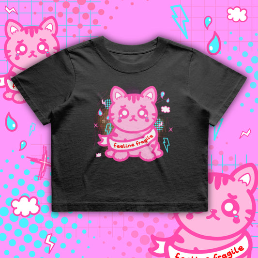 Black crop tee by Innabox featuring a pink crying cartoon cat with “feeline fragile” text on the front. Boxy oversized fit crop top made from 100% cotton. Disability positive graphic t shirt designed to uplift people with chronic illness and hidden disabilities.
