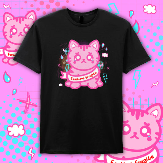 Black unisex T-shirt by Innabox featuring a cute pink cartoon cat with teary eyes and the slogan “Feeline Fragile”. Disability awareness clothing designed to support chronic illness and hidden disabilities, with bold kawaii style artwork on soft cotton fabric.
