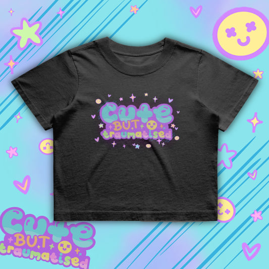 Black cropped t-shirt featuring colourful “Cute But Traumatised” slogan in pastel bubble lettering with stars and hearts. Boxy oversized fit crop tee by Innabox, a disability inspired brand supporting chronic illness and hidden disabilities. Fun, expressive graphic tee for alternative fashion lovers.
