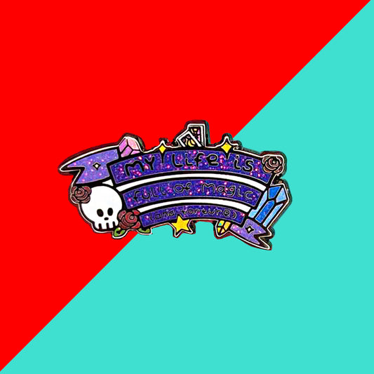The My Life is Full of Magic & Torture Glitter Enamel Pin on a red and blue background. The glittery finish enamel pin badge features a purple banner sash of black text reading 'my life is full of magic (and torture)' with yellow sparkles, crystals, red roses, tarot cards and a skull head.
