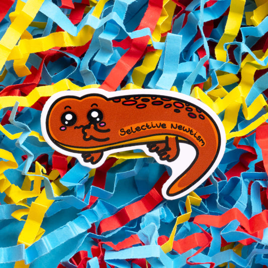 Innabox Selective Newtism sticker showcasing an adorable orange newt with red spots, and 'Selective Newtism' text. The colourful shredded paper background adds a playful contrast, highlighting this uplifting product aimed at those with hidden disabilities.
