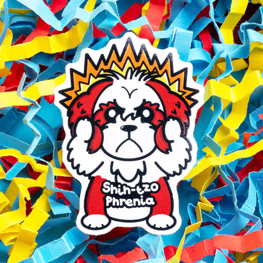 Colourful Innabox sticker of a cartoon Shih Tzu with an intense expression, fiery aura, and the pun 'Shih-tzo Phrenia.' This disability-inspired sticker is designed to uplift those with chronic illnesses. Set against a vibrant background of red, blue, and yellow confetti strips.