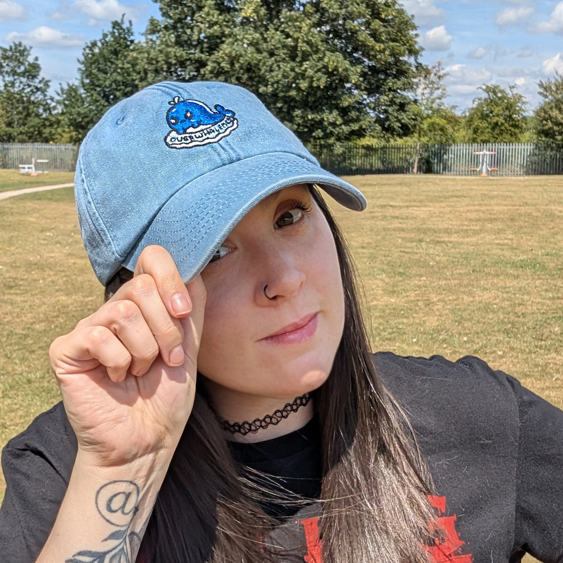 Model wearing the Overwhalemed cap by Innabox featuring a crying blue whale design. Gentle, supportive fashion piece inspired by chronic illness experiences.