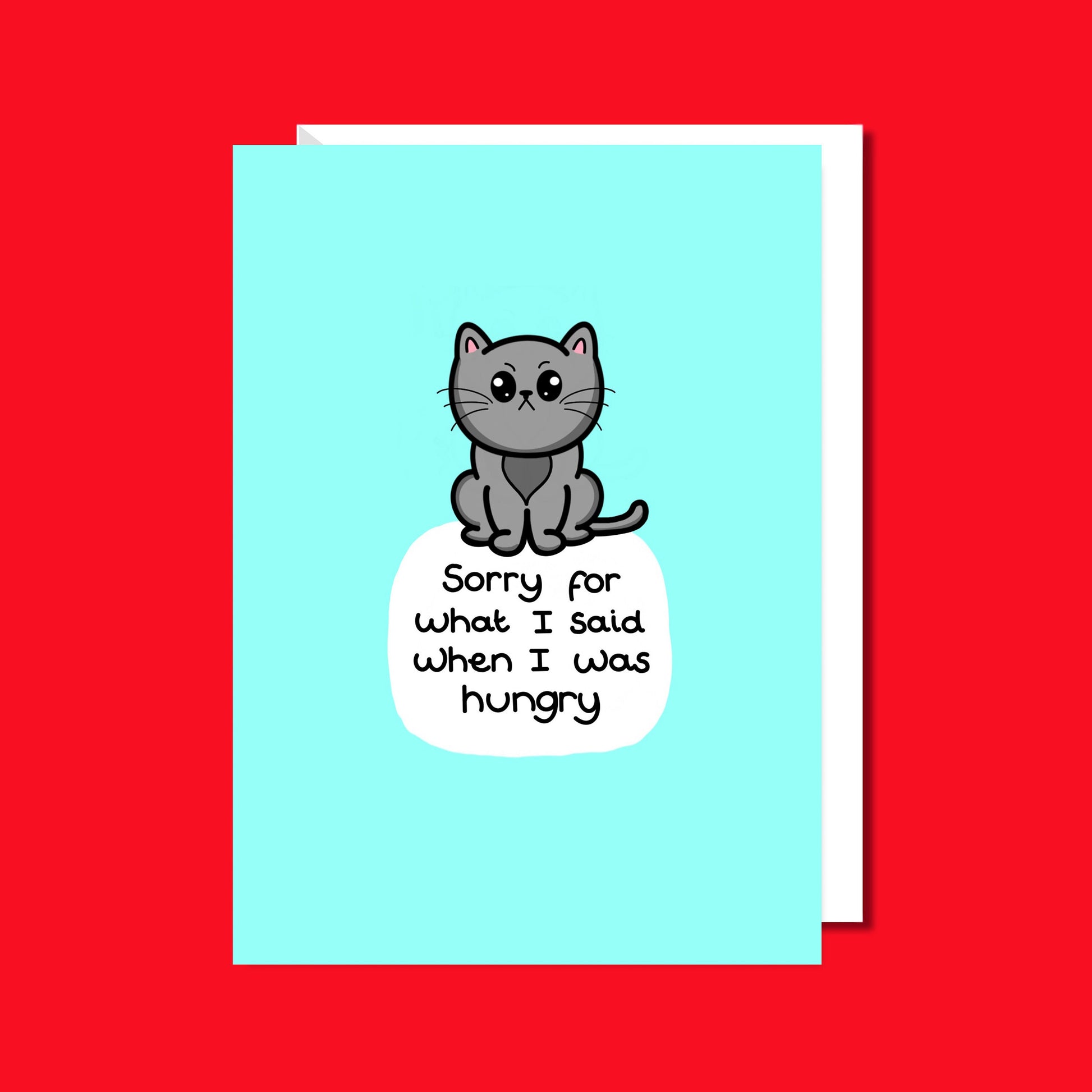 The Sorry For What I Said When I Was Hungry Cat Card on a red background with a white envelope underneath. A light blue a6 greeting card with an angry grey cat and white bubble with black text reading 'sorry for what I said when I was hungry'.