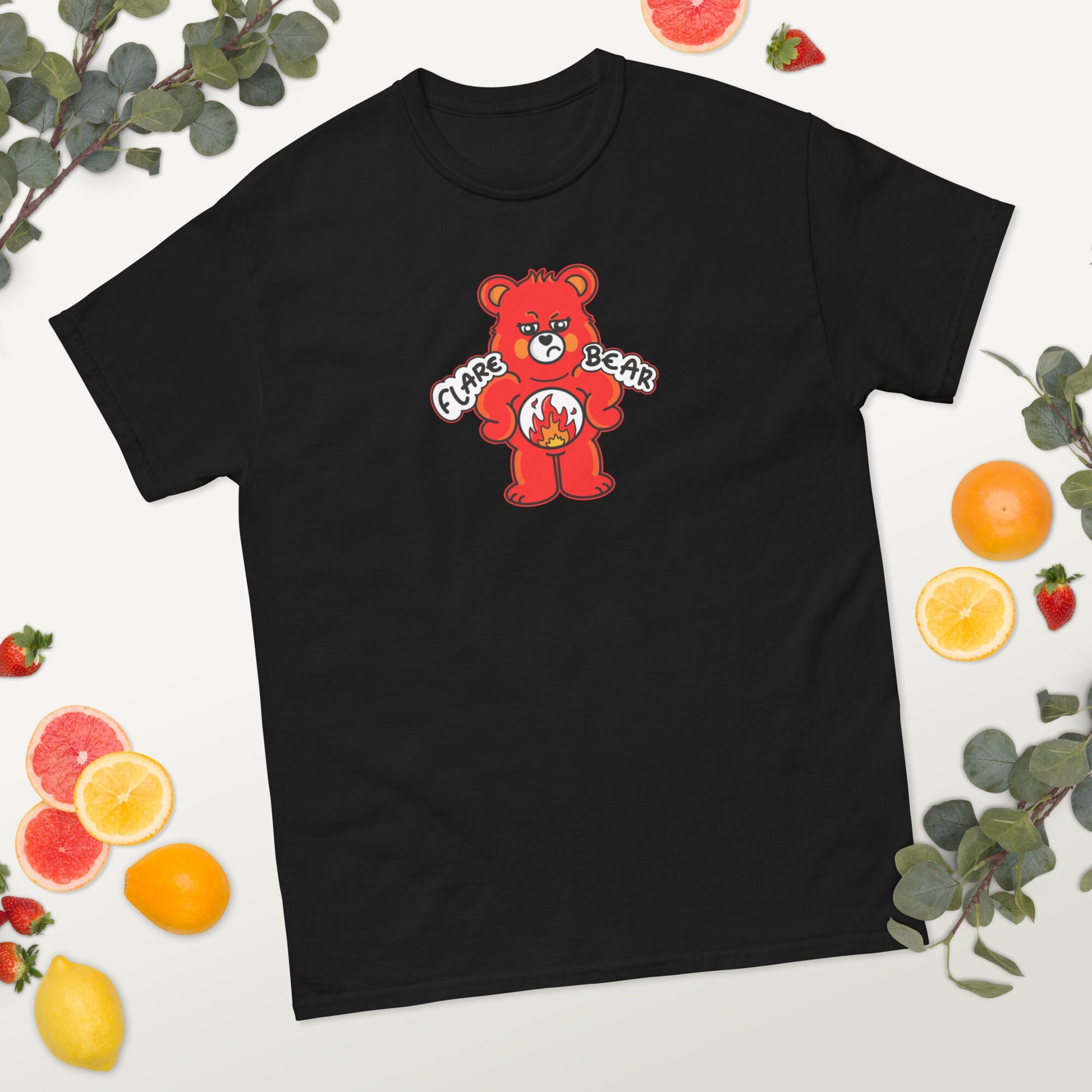 Flare Bear T-shirt a white background with fruit slices and foliage. The black short sleeve tshirt is of a red bear with a fed up expression and hands on its hips. There is a white circle on its belly with flames inside. Flare Bear is written on the middle. The tshirt is designed to raise awareness for chronic illness flare ups.